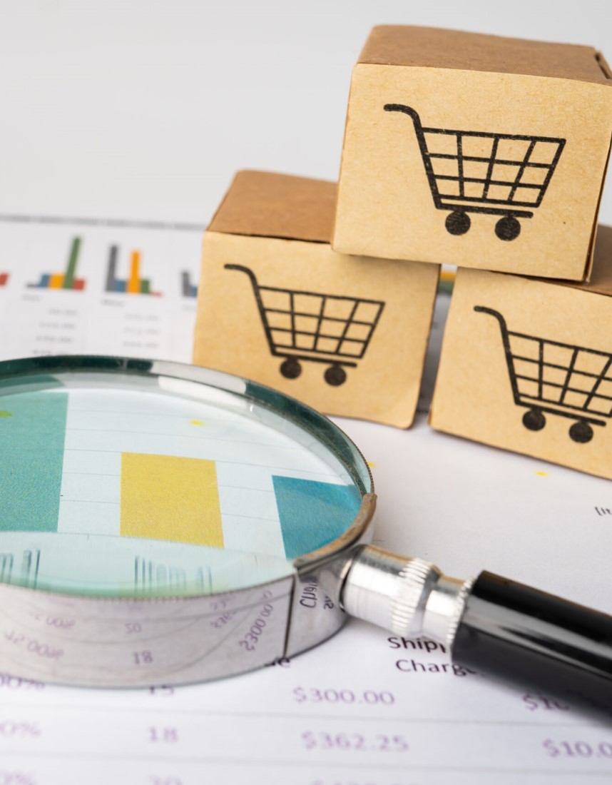 Symbolbild für Multibuyer Analytics: eine Lupe und kleine Kartons, auf denen Warenkörbe zu sehen sind.
