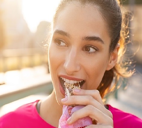 Eine Frau beisst in einem Müsliriegel. Symbolbild für die Multibuyer Analyse in udo